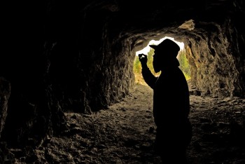 Illustrating the mining history of the Black Hills with this photo of a prospector checking out some ore is accomplished by carefully placing a silhouette against the bright opening of a mine. Photoshop artistry later added a beard to the “prospector” figure.