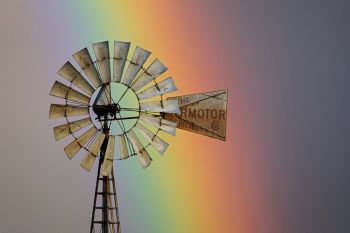 A prairie windmill with a rainbow background in rural Lincoln County.