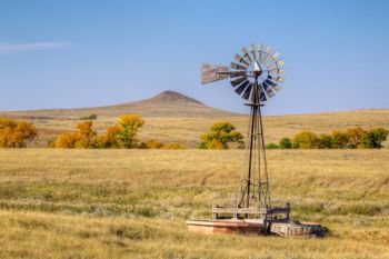 A prairie windmill with a small Harding County butte in the distance.