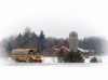 Motoring through the snow, a Deuel County school bus passes a farm near Clear Lake.