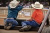 Two young cowboys watch intently as barrel racers compete in the Days of  76 arena.
