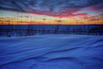 Snow on the edge of a field under a colorful post-sunset sky in Minnehaha County.