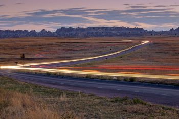 A composite of long exposures shows headlights heading in and out of Badlands National Park in the blue hour.