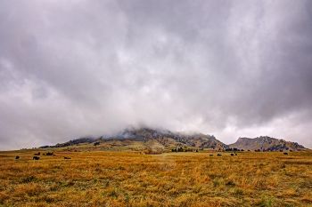 Low clouds and a light rain converge on Bear Butte.